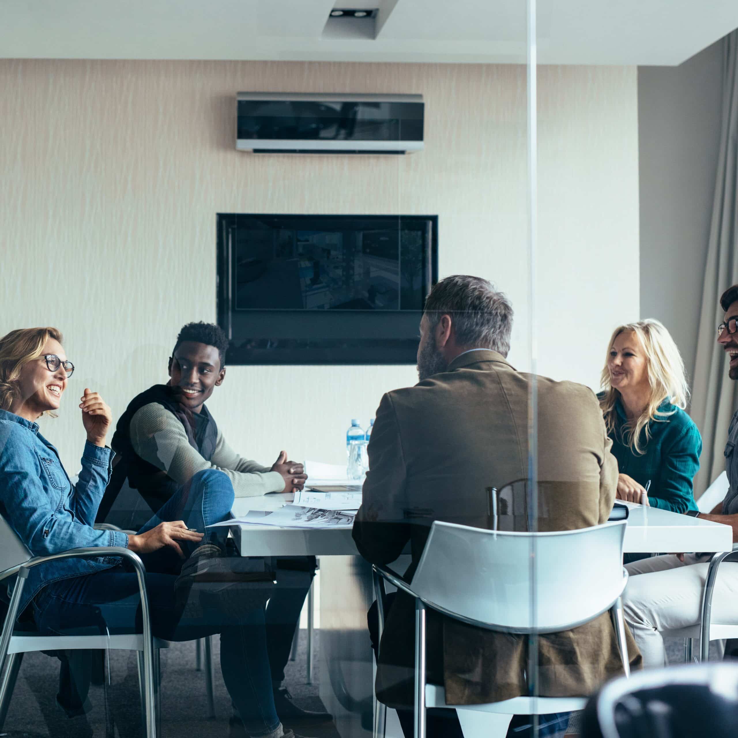 A diverse leadership team in discussion around a meeting table, representing collaborative approaches to workplace health and safety.
